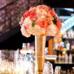 St. Pete Wedding Reception Table Decor with Candlelight and Ivory and Coral Bouquet of Flowers in Tall Gold Centerpieces