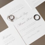 Elegant Gray Script on White Wedding Invitation Suite with Engagement Ring and White Gold Wedding Band and Black Metal Groom's Band