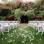 Outdoor Garden Wedding Ceremony Decor with White Folding Chairs with Pink and White Flowers, Pearl Beads, and Gold Ribbon | St Pete Wedding Ceremony Venue The Sunken Gardens