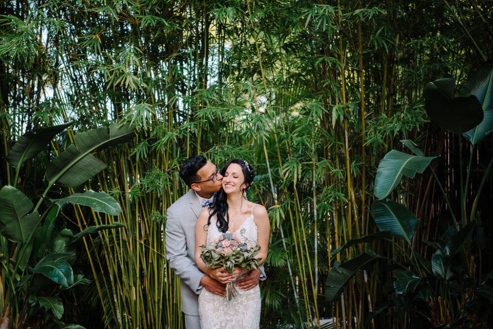 Bride in lace wedding dress with blush and gray bouquet with groom in gray suit